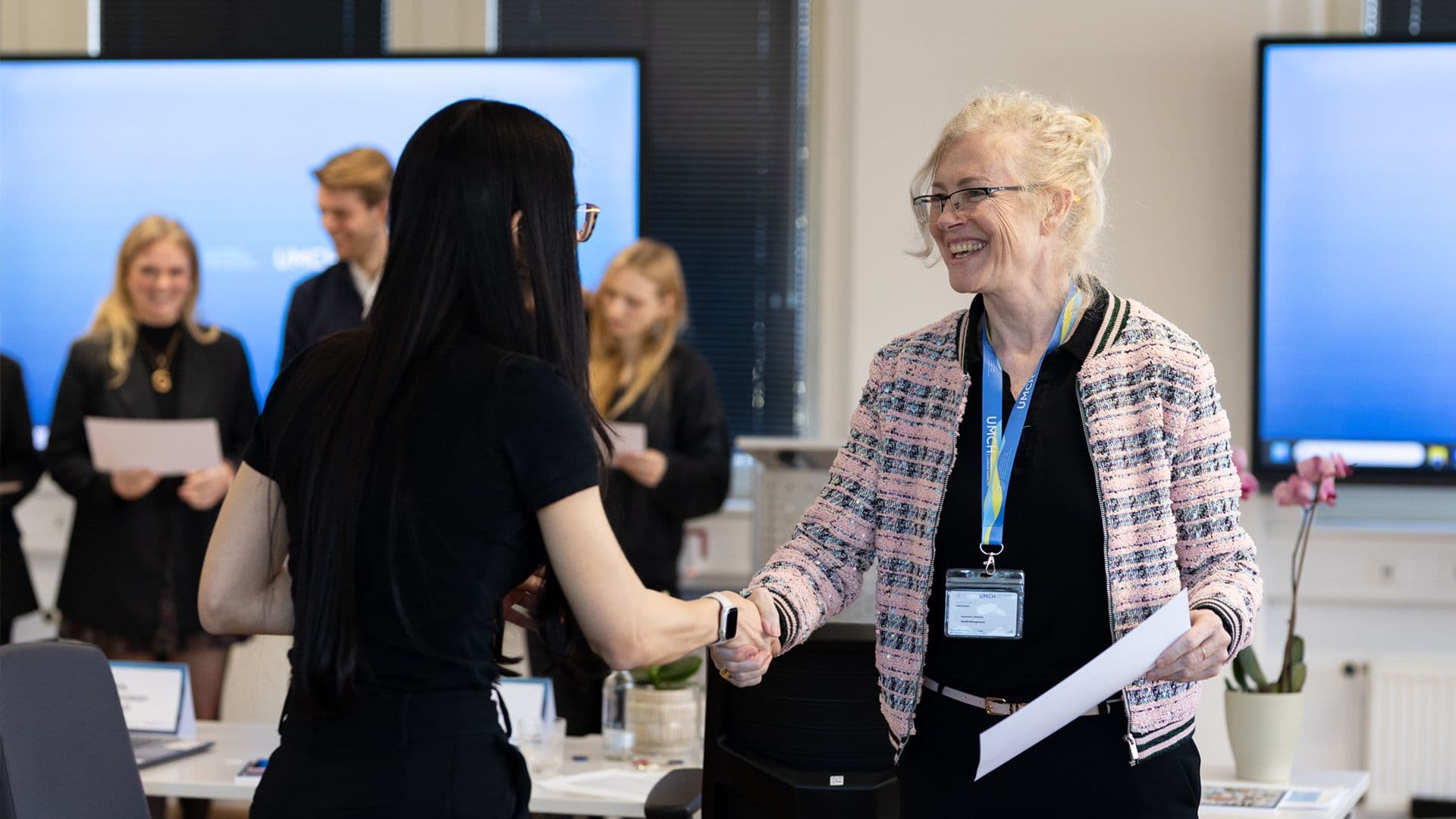 Participants greeting each other at a certificate ceremony during a UMCH event.
